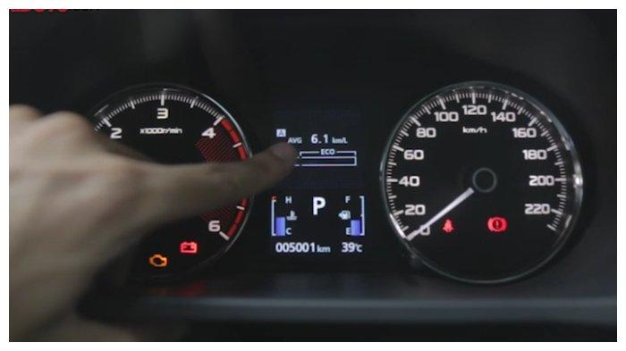 Sebuah tangan menunjuk ke arah indikator bensin pada mobil